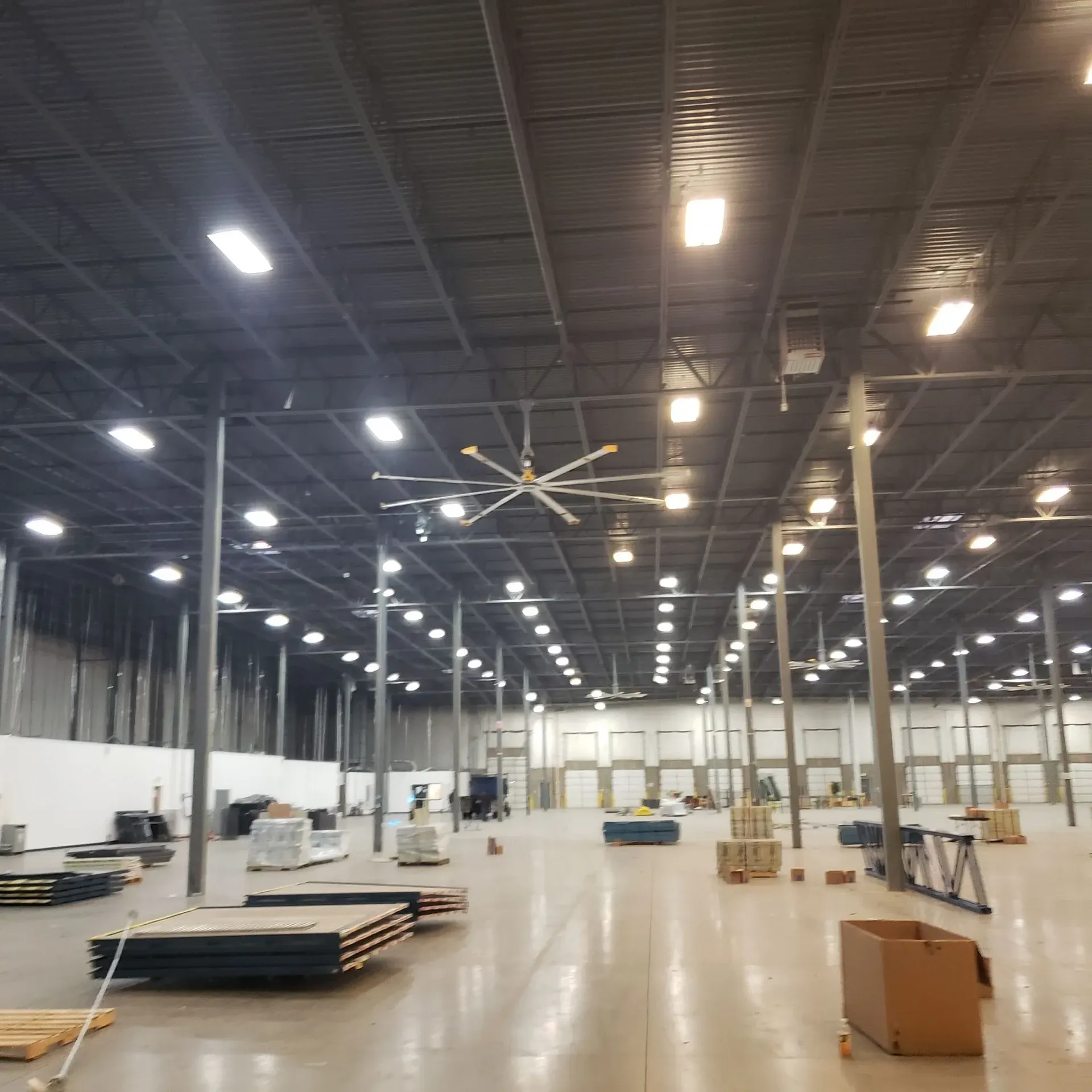 A large warehouse with lots of lights and a ceiling fan