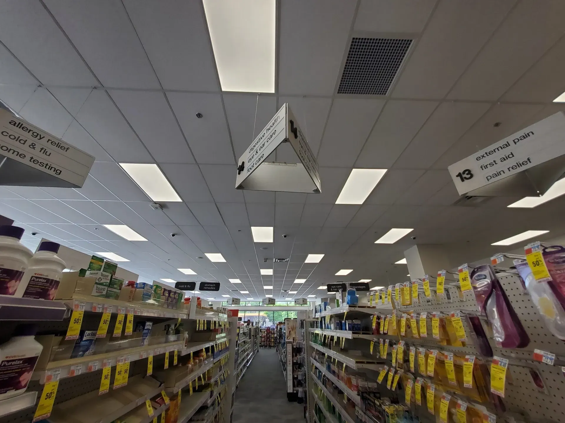 The inside of a pharmacy with shelves and signs hanging from the ceiling.