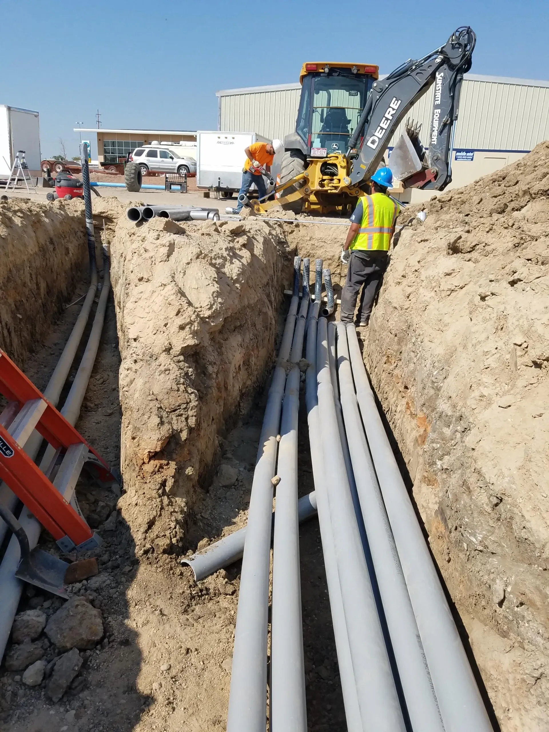 A deere excavator is digging a trench filled with pipes