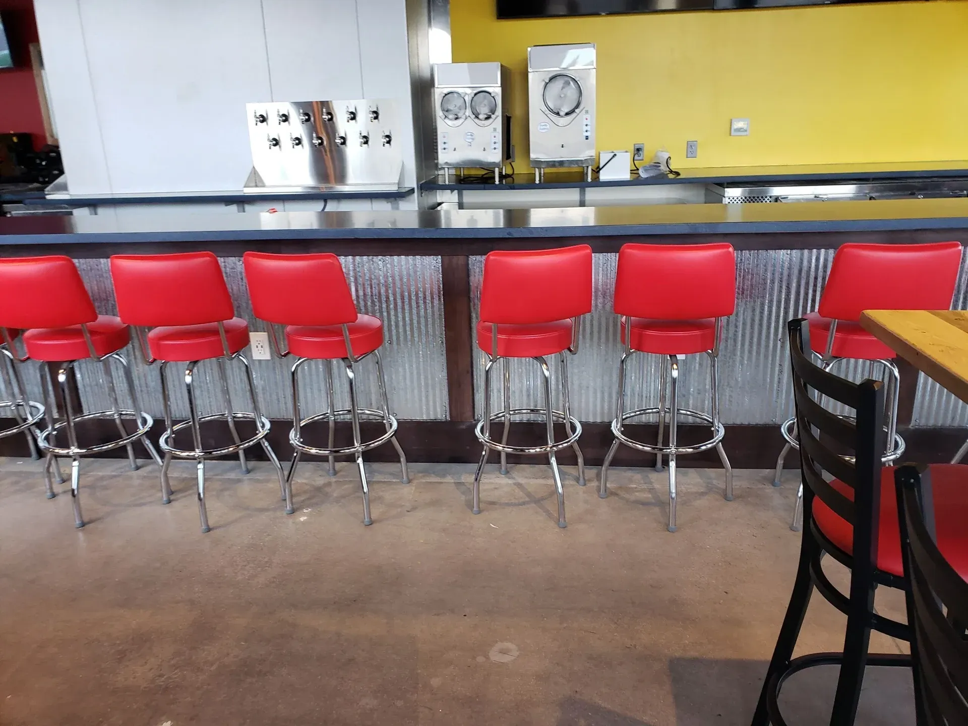 A row of red bar stools are lined up in front of a counter