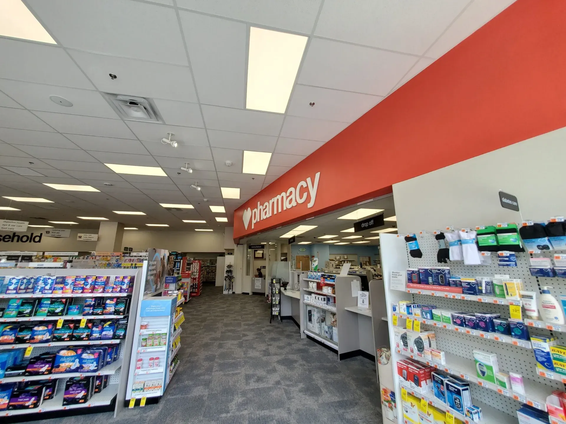 The inside of a pharmacy with a red sign that says pharmacy.