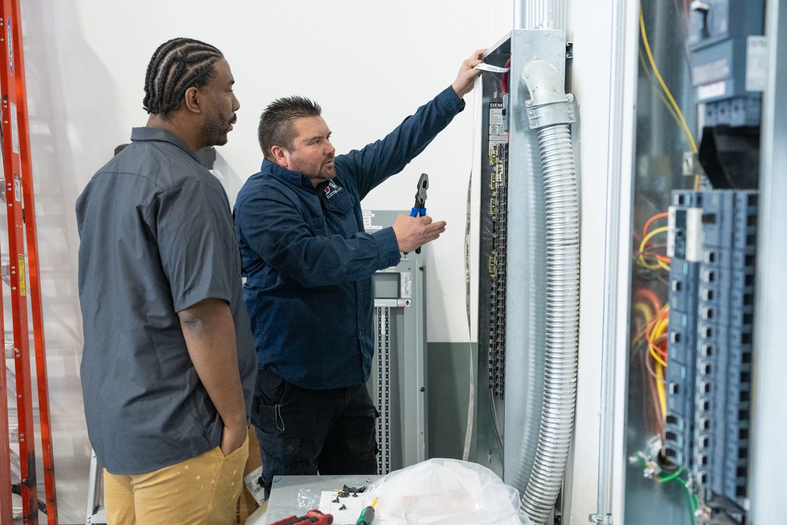 B & W Services Technicians are working on a electrical box in a room.