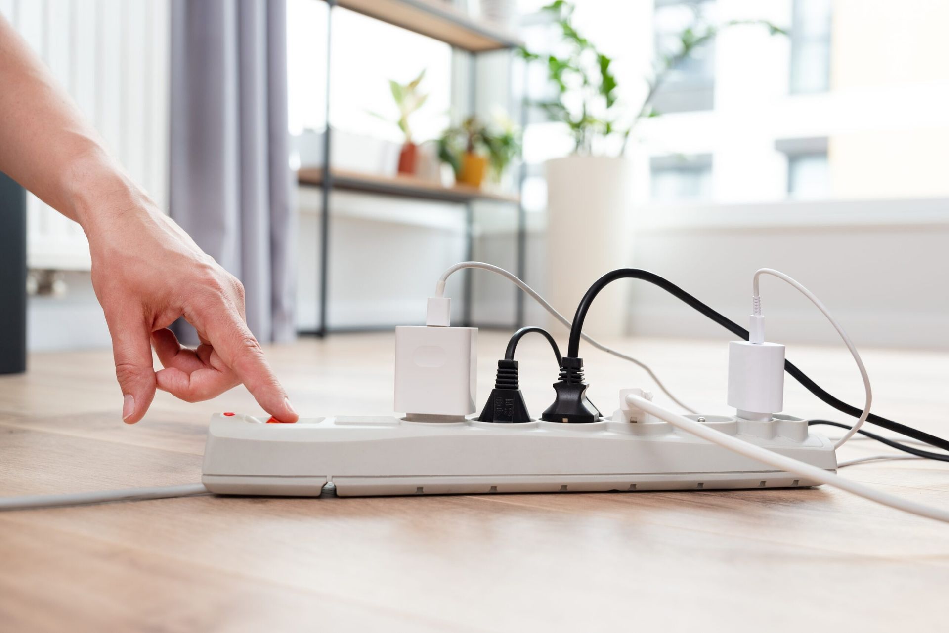 A person is pressing a button on a power strip.