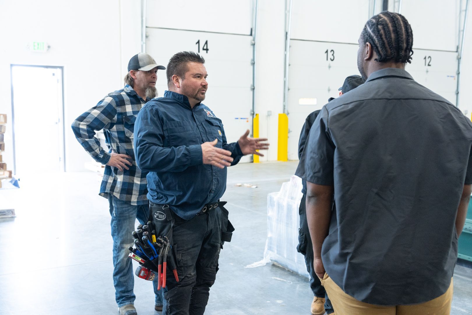 A group of B & W Services Technician are standing in a warehouse talking to each other.