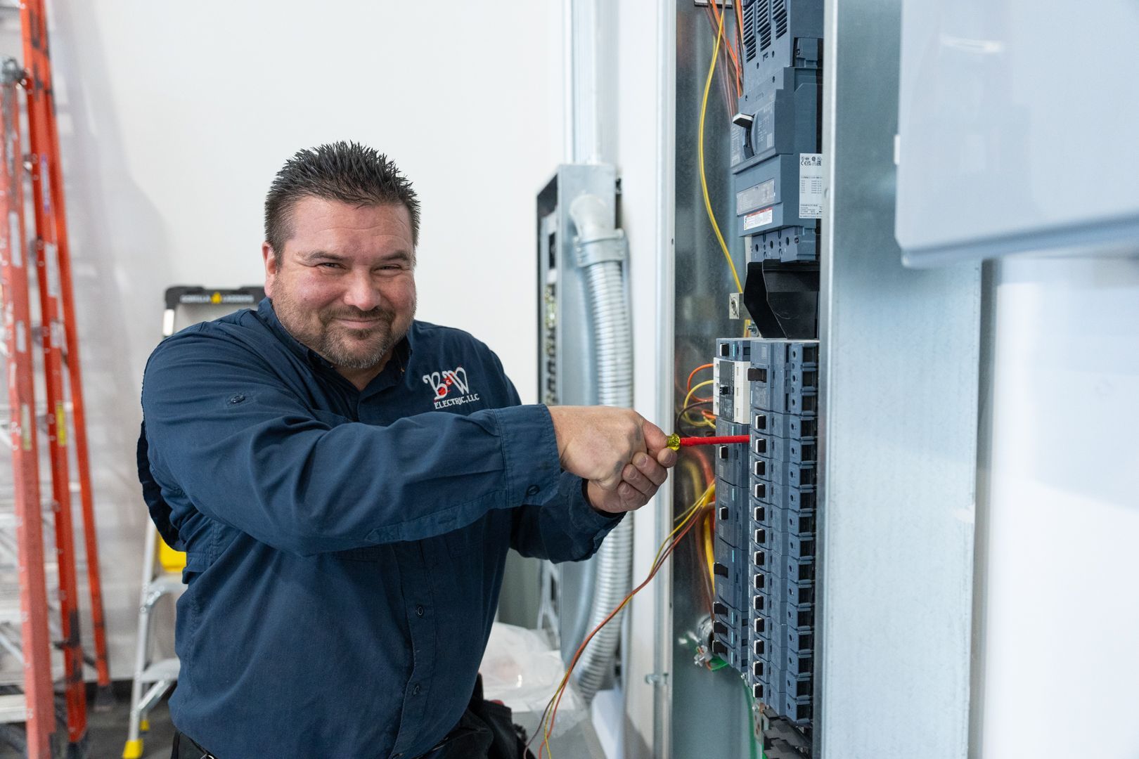 B & W Services Technician is working on an electrical box with a screwdriver.