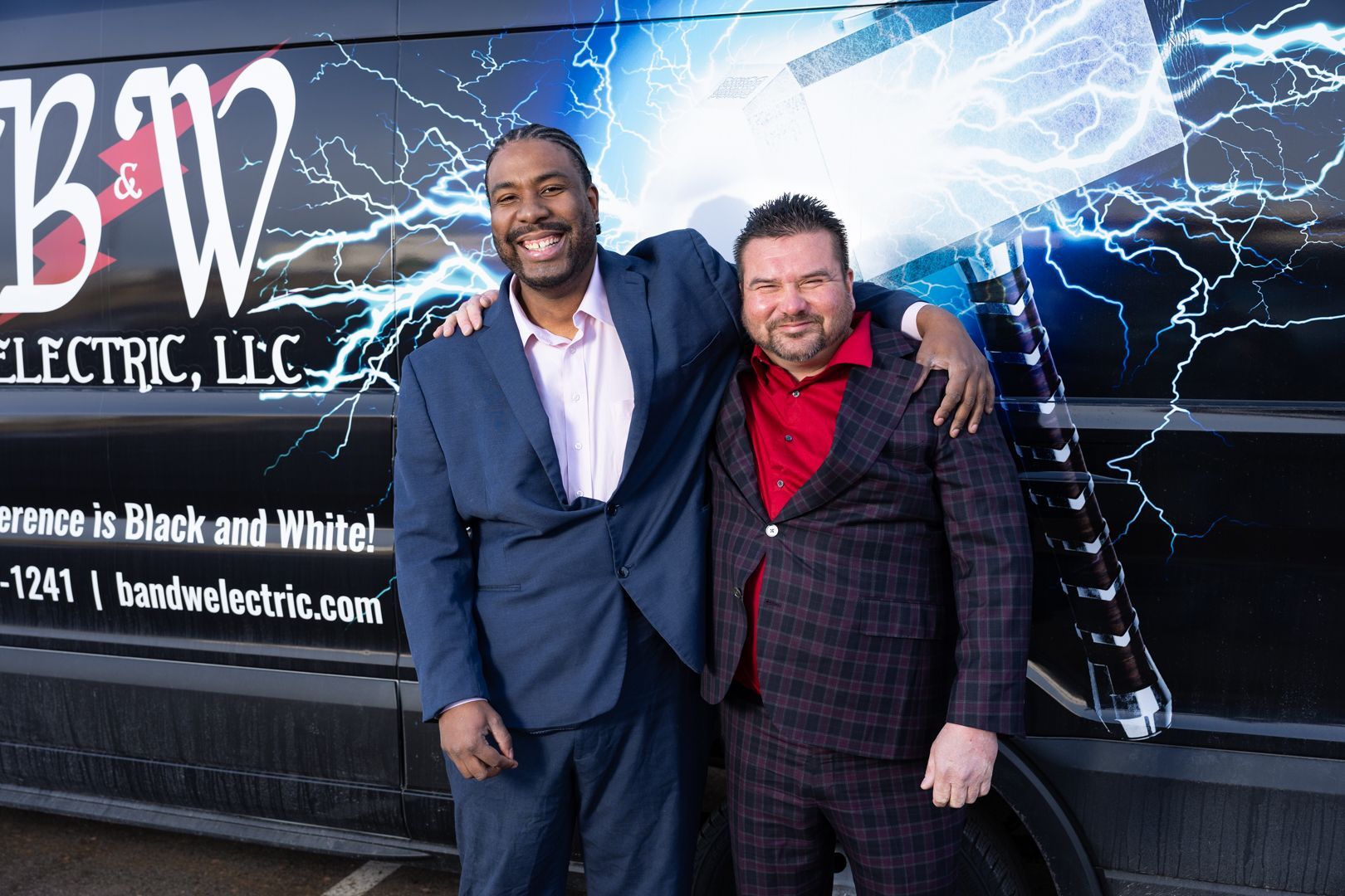 Two men are posing in front of a van that says bw electric llc