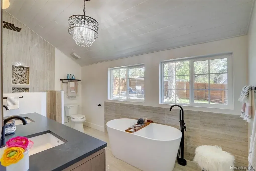 A bathroom with a tub , sink , toilet and window.