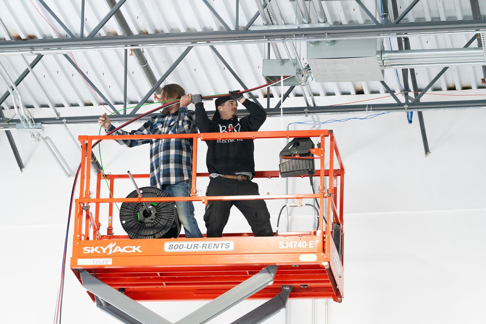 Two B & W Services Technician are standing on a scissor lift working on a ceiling.