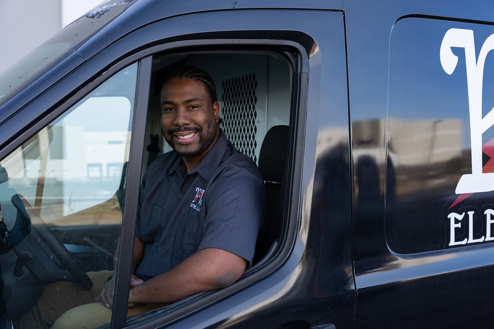A man is sitting in the driver 's seat of a black van.