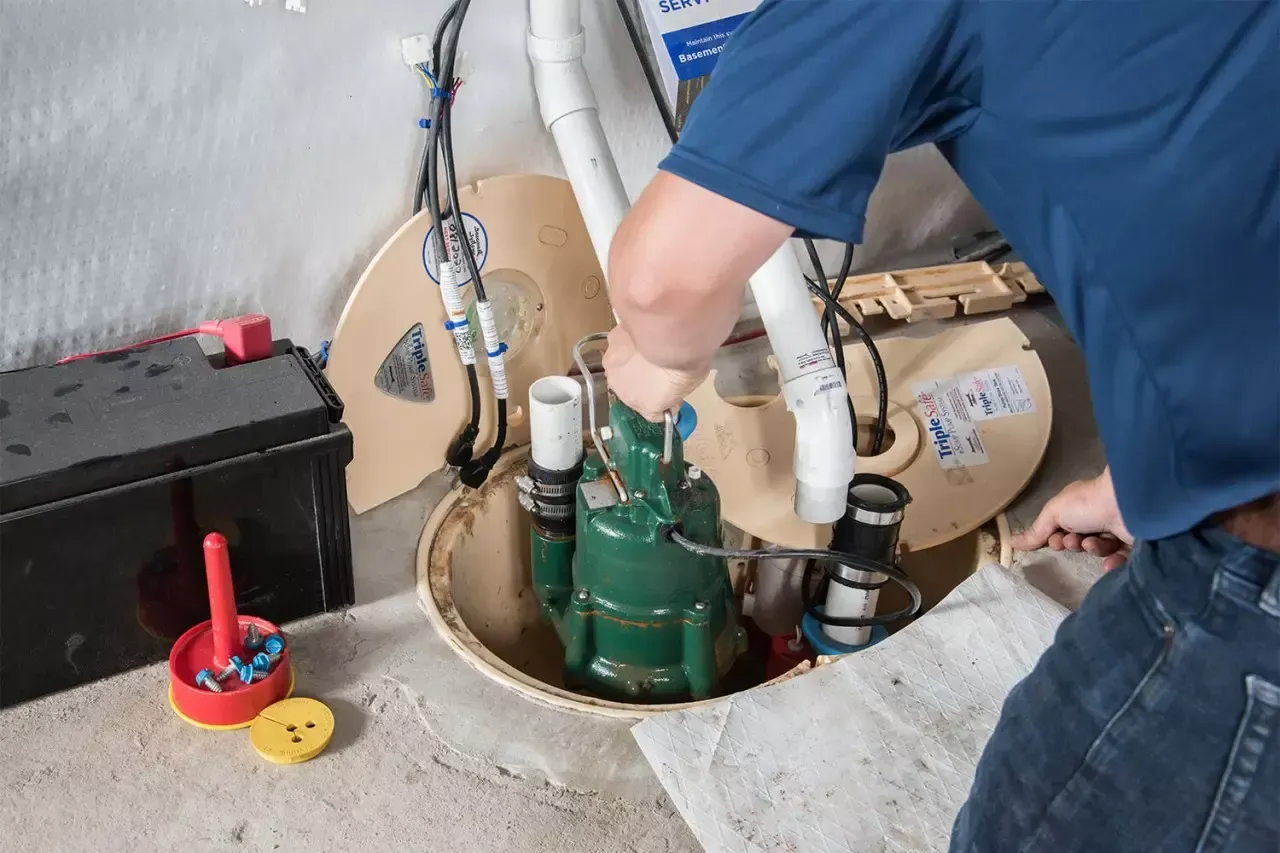 A B & W Services Technician is fixing a sump pump in a basement.