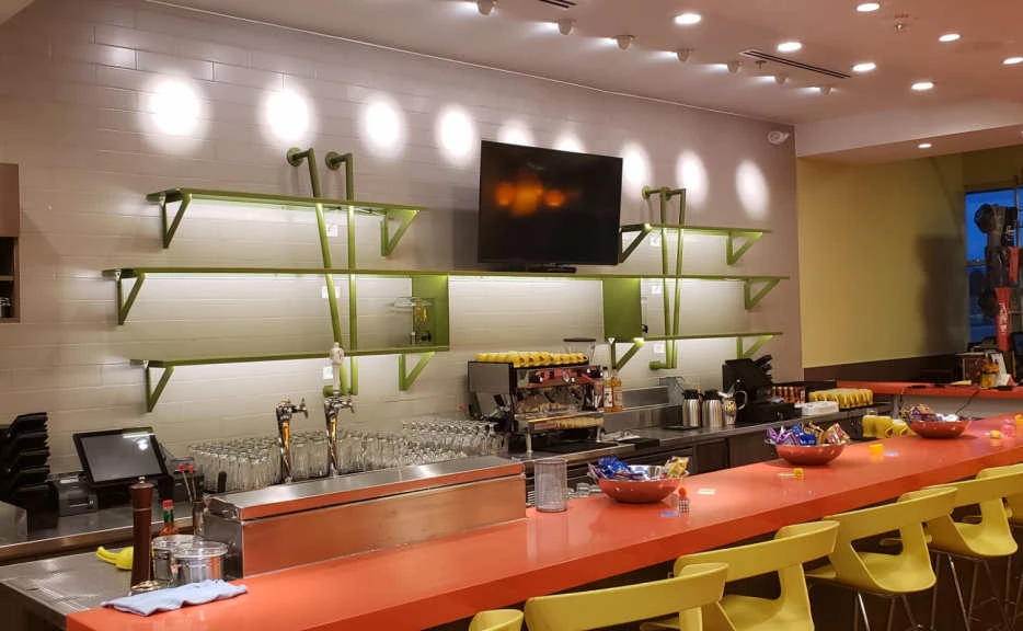 A restaurant with a long bar and a television on the wall.
