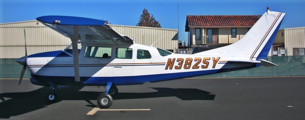 Blue and white Cessna airplane on a tarmac; sunny day.