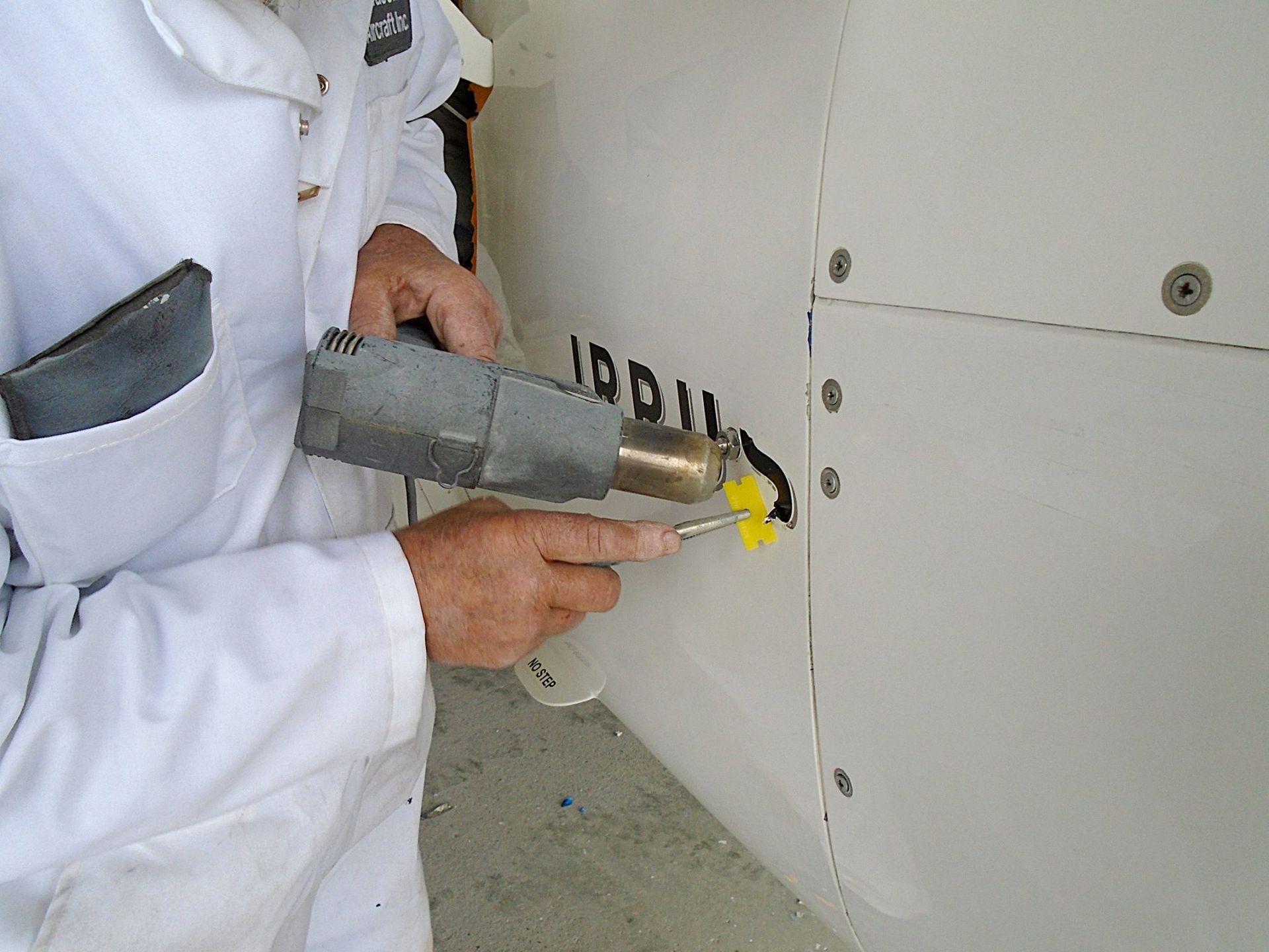 Person using a heat gun to remove black letters from a white surface.