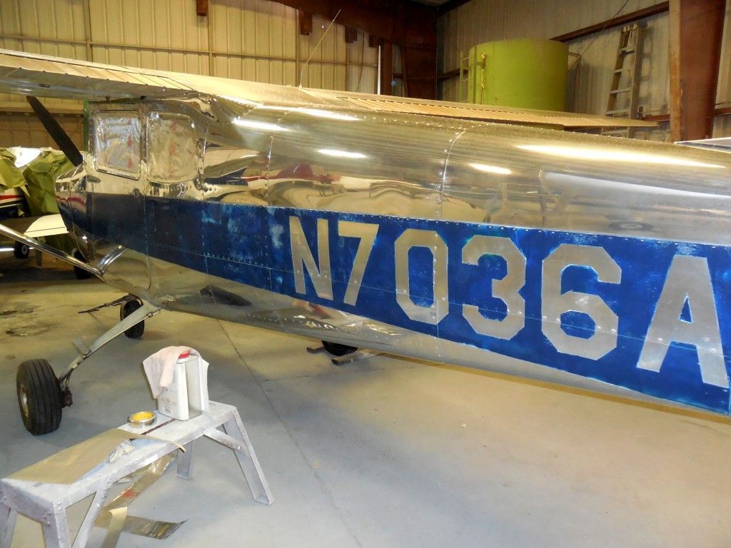 Side view of a polished silver and blue airplane in a hangar, with registration number N7036A.