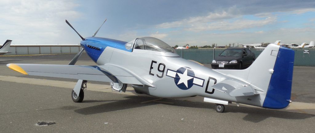 Silver and blue P-51 Mustang airplane on a tarmac. The aircraft has a white star insignia and