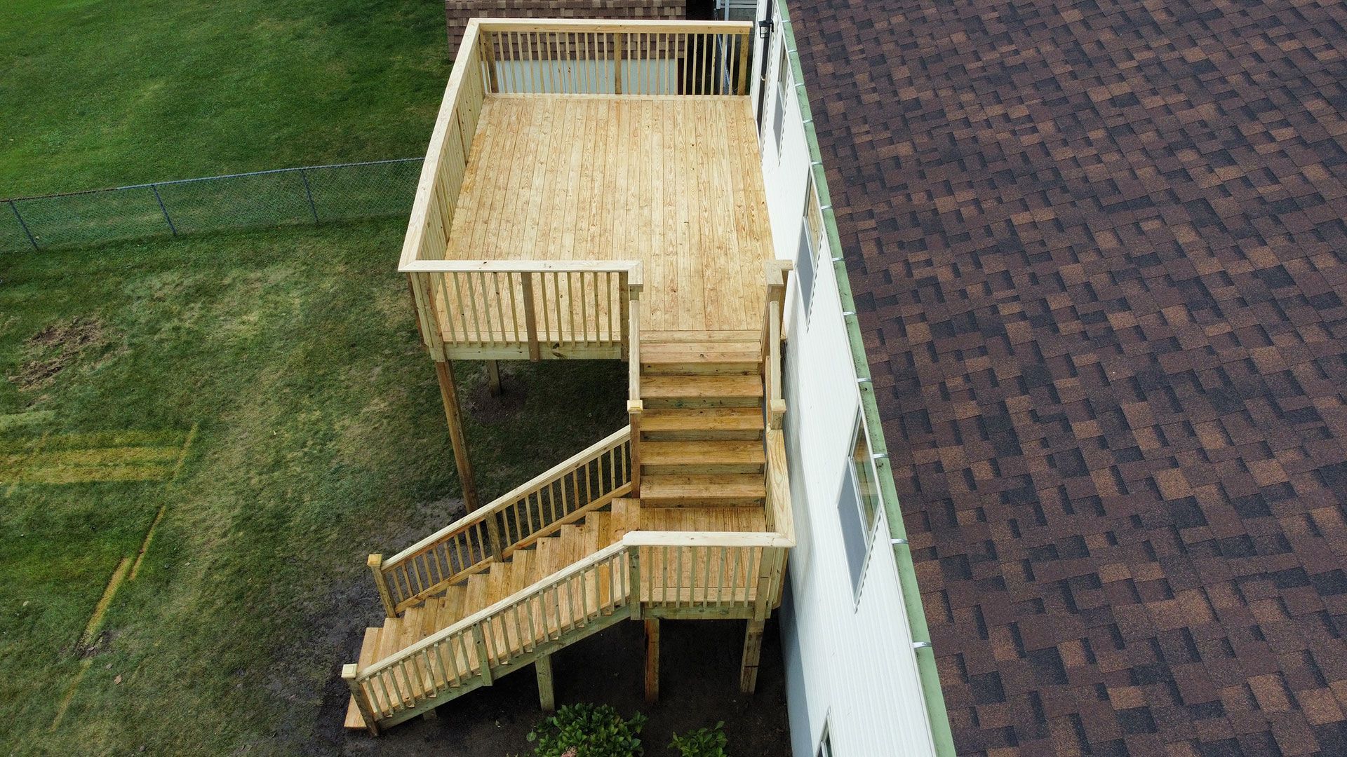 A white house with a wooden deck in front of it.