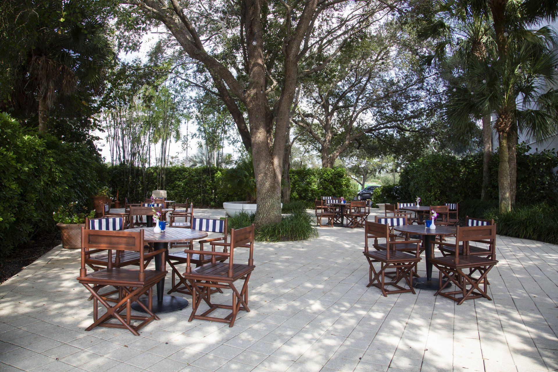 A patio with tables and chairs under trees