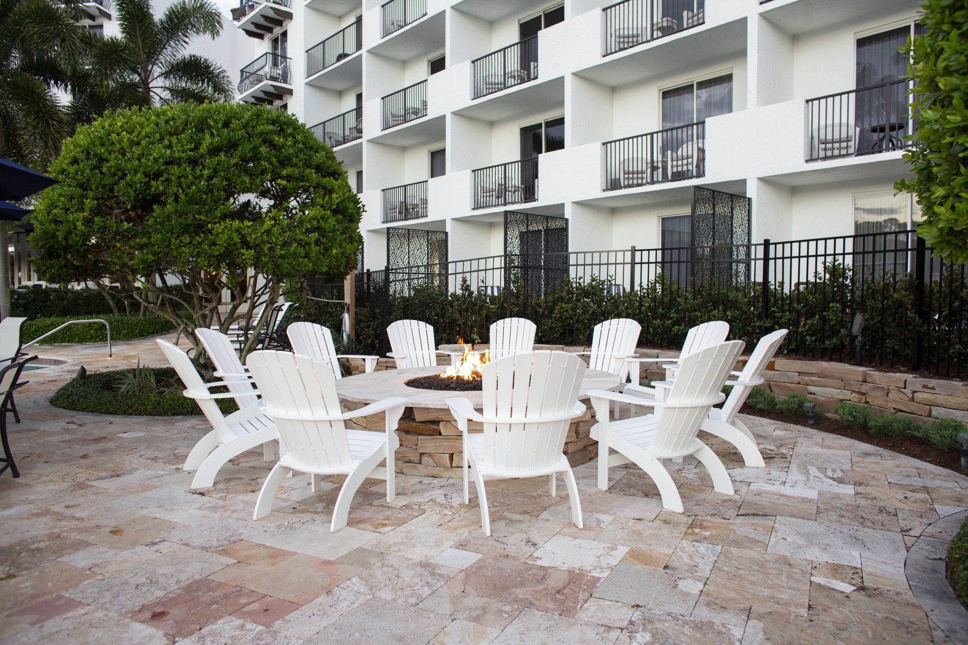 A patio with a fire pit and chairs in front of a building