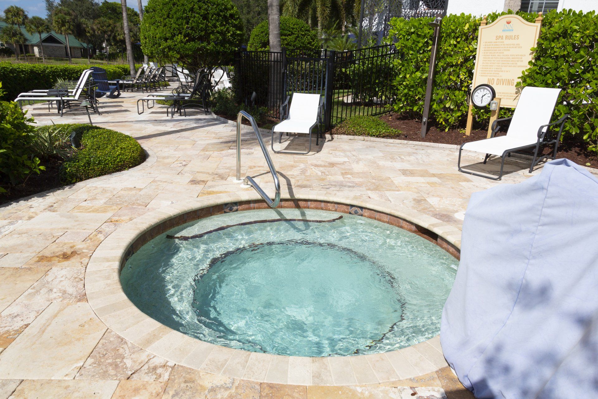 A hot tub is surrounded by chairs and a sign that says ' swimming pool ' on it