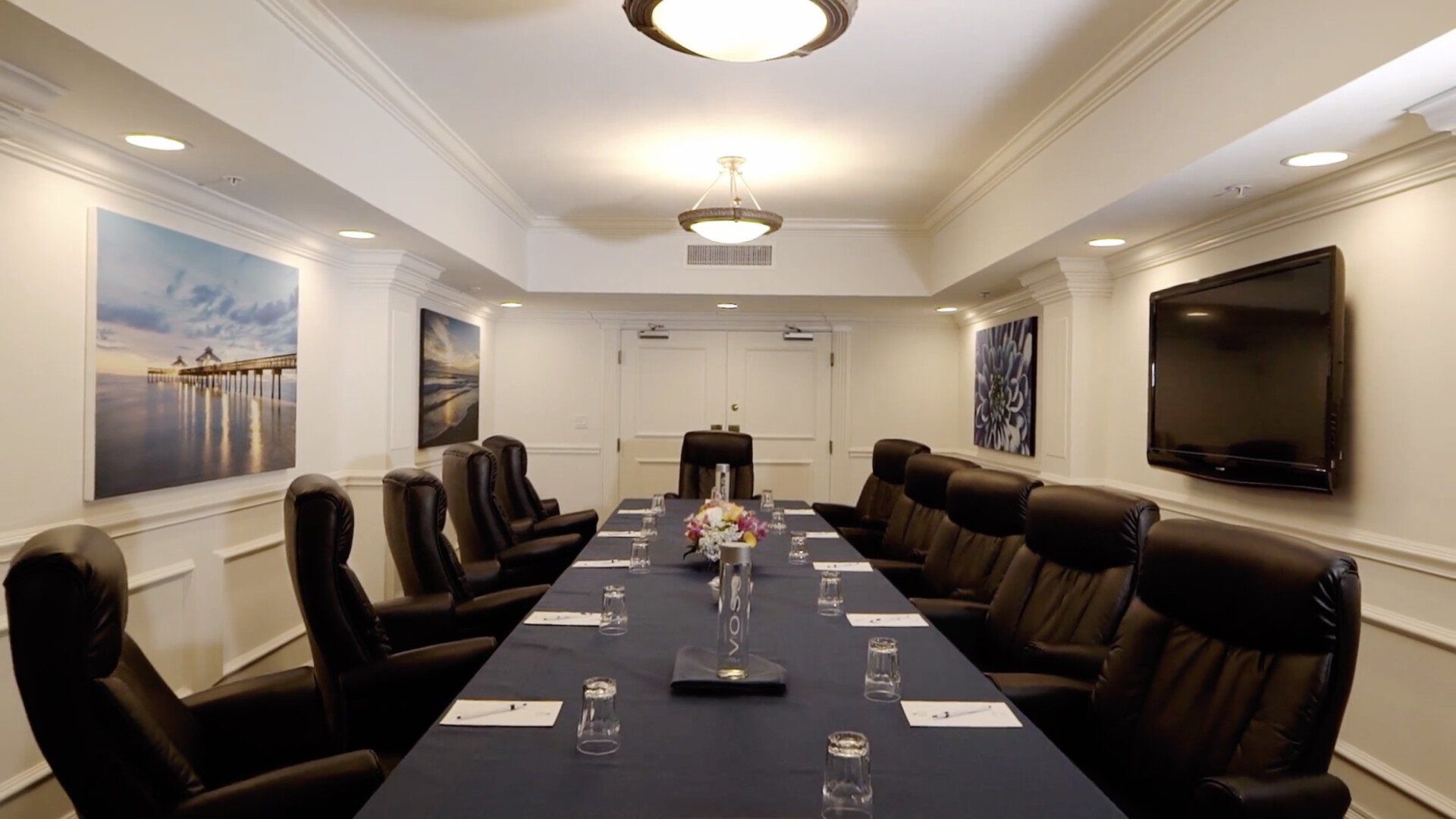 A conference room with a long table and chairs and a flat screen tv on the wall.