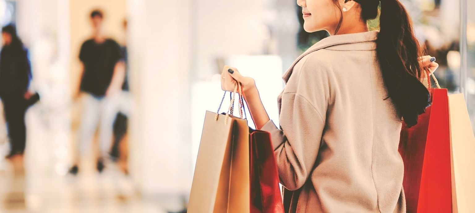 A woman is holding shopping bags in a mall.