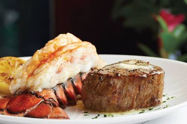 A white plate topped with a steak and lobster tail