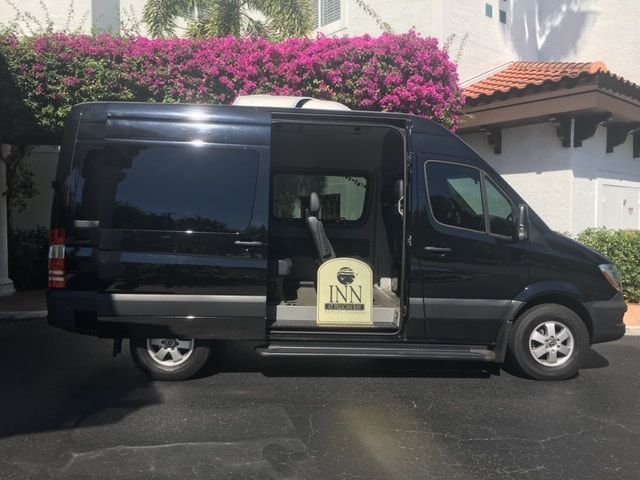 A black van is parked in front of a building that says inn