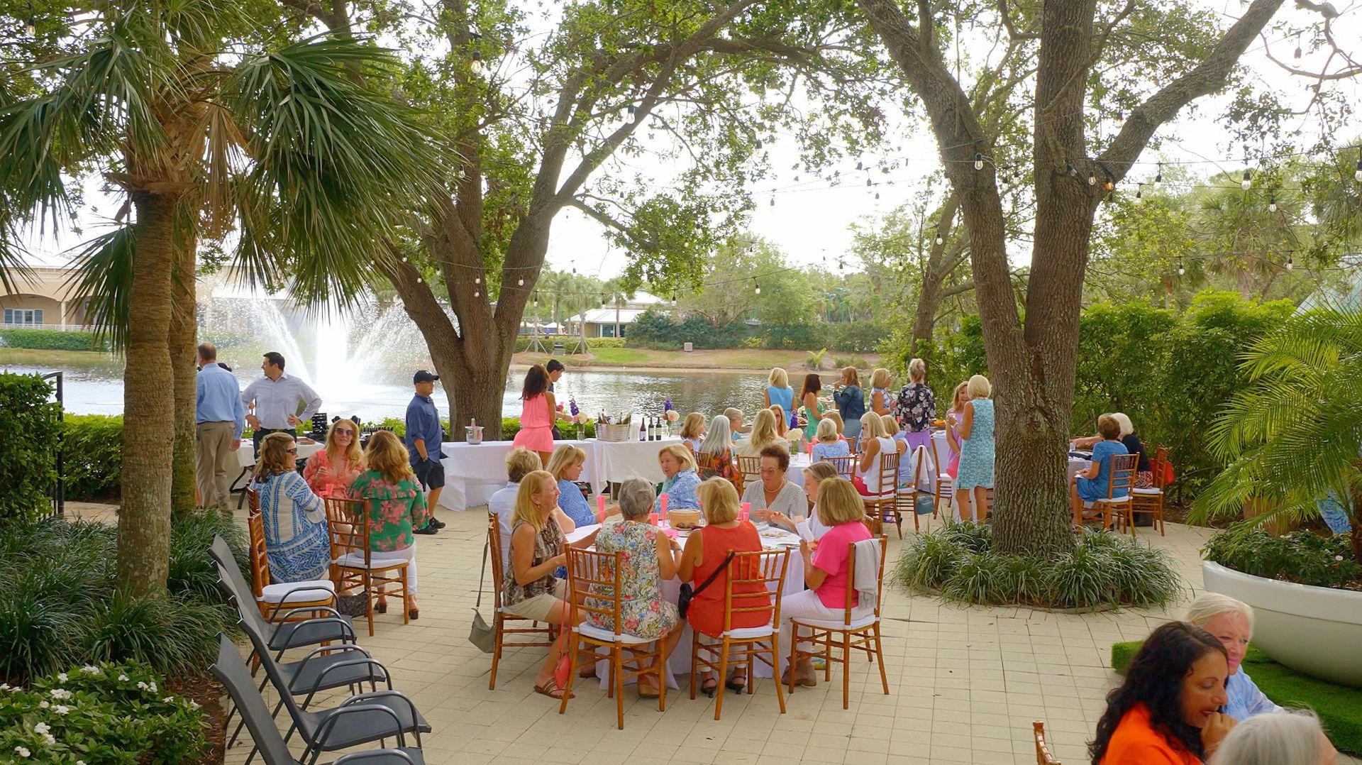 A group of people are sitting at tables in a park.