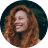 Smiling woman in a red top with curly hair against a dark background