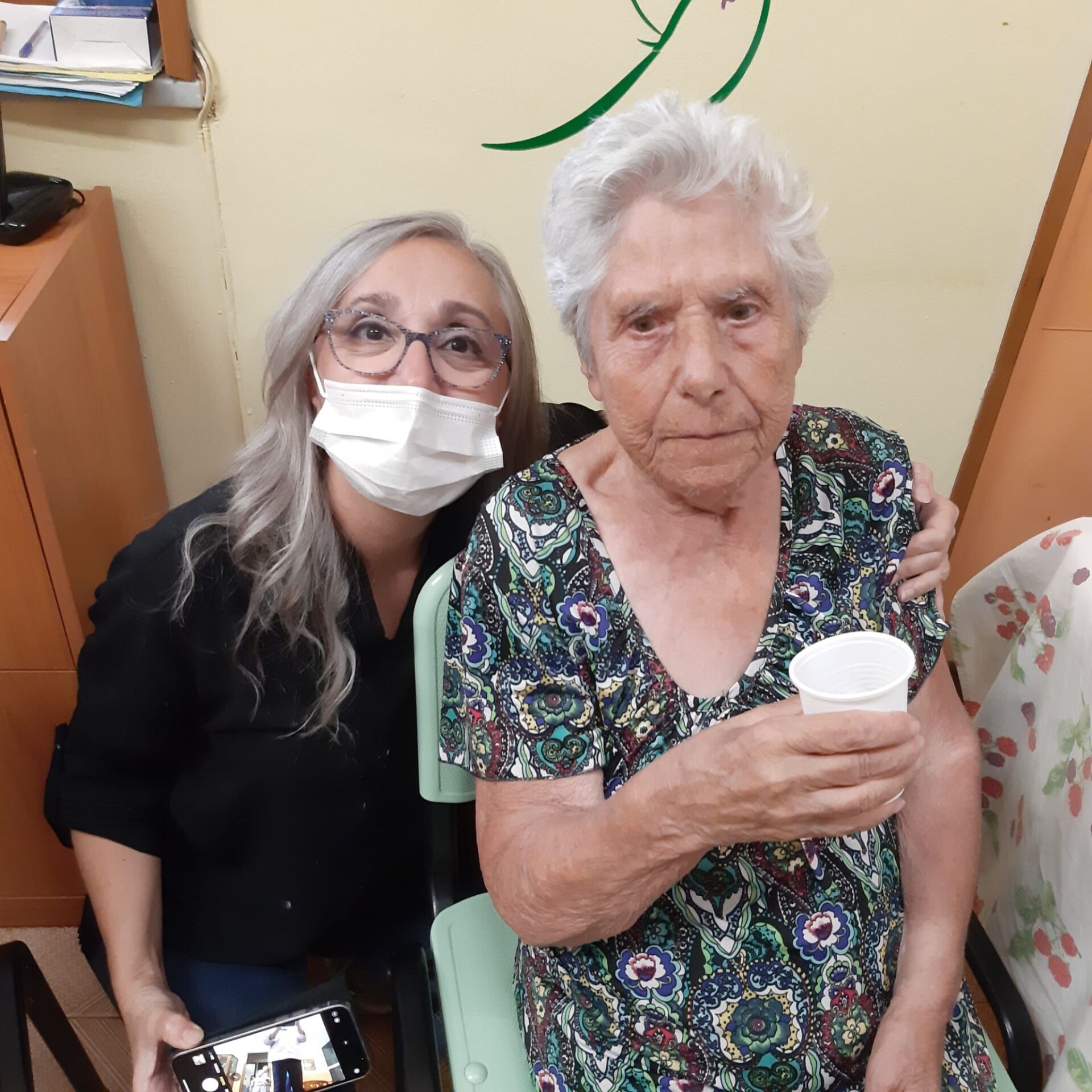 anziana con bicchiere in mano e assistente