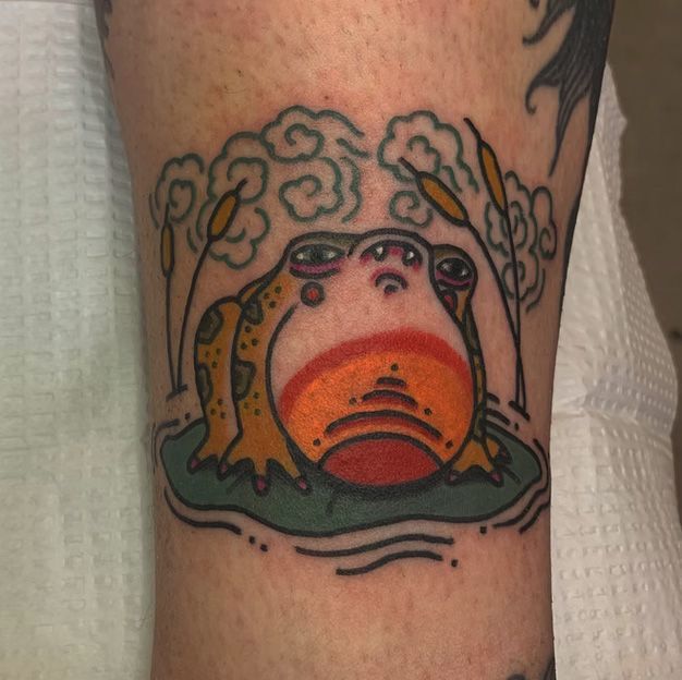 A person has a tattoo of a frog on their leg