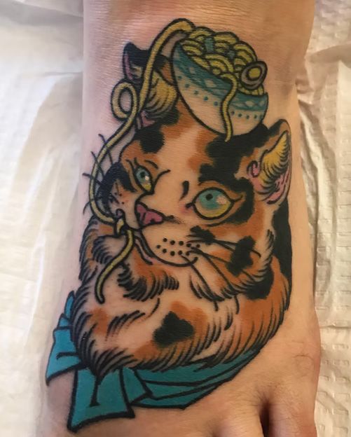 A tattoo of a cat with a bowl of noodles on its head