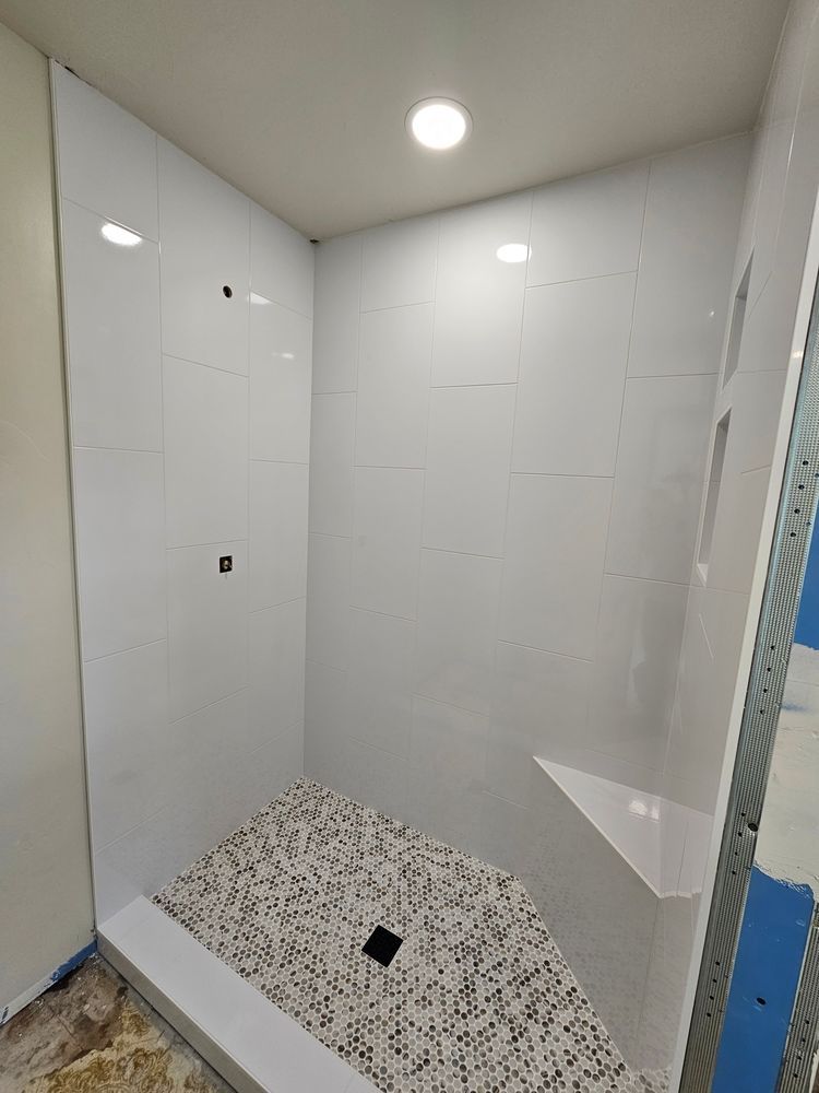 White tiled shower with pebble floor and built-in seat.