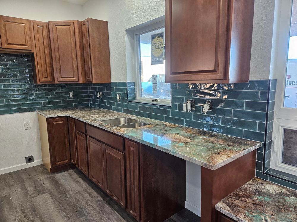 Kitchen with brown cabinets, green backsplash, and granite countertops.