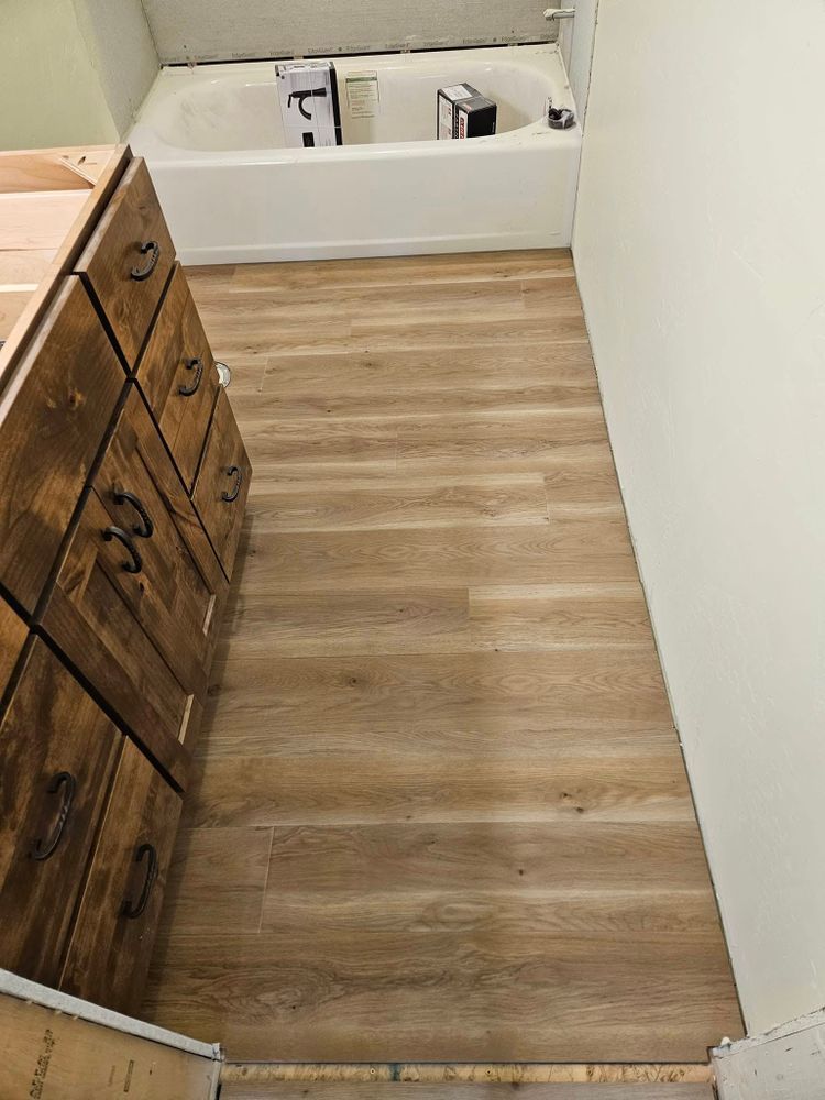 Bathroom with light wood-look flooring, a dark wood vanity, and a white bathtub.