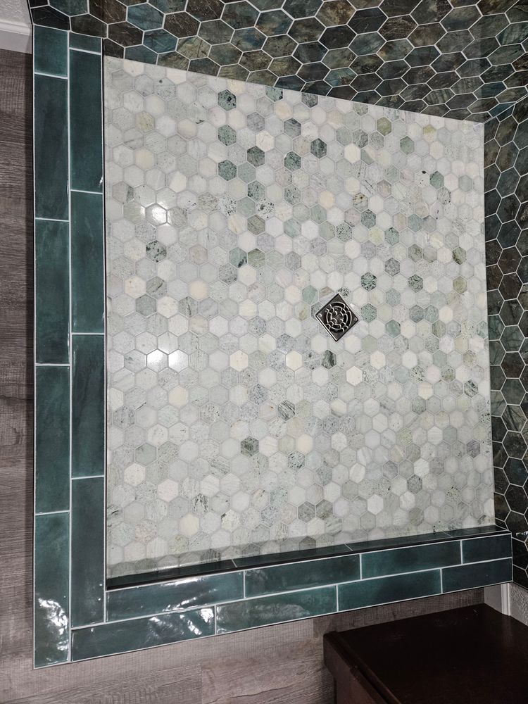 Shower with hexagon mosaic tile floor, teal trim, and bench; close-up.