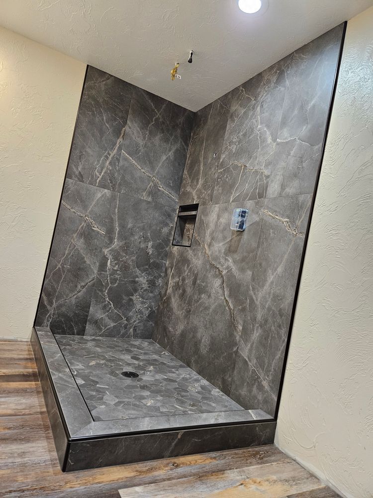 Tile shower with gray marble-look walls, dark gray floor, built-in niche, and chrome fixtures.