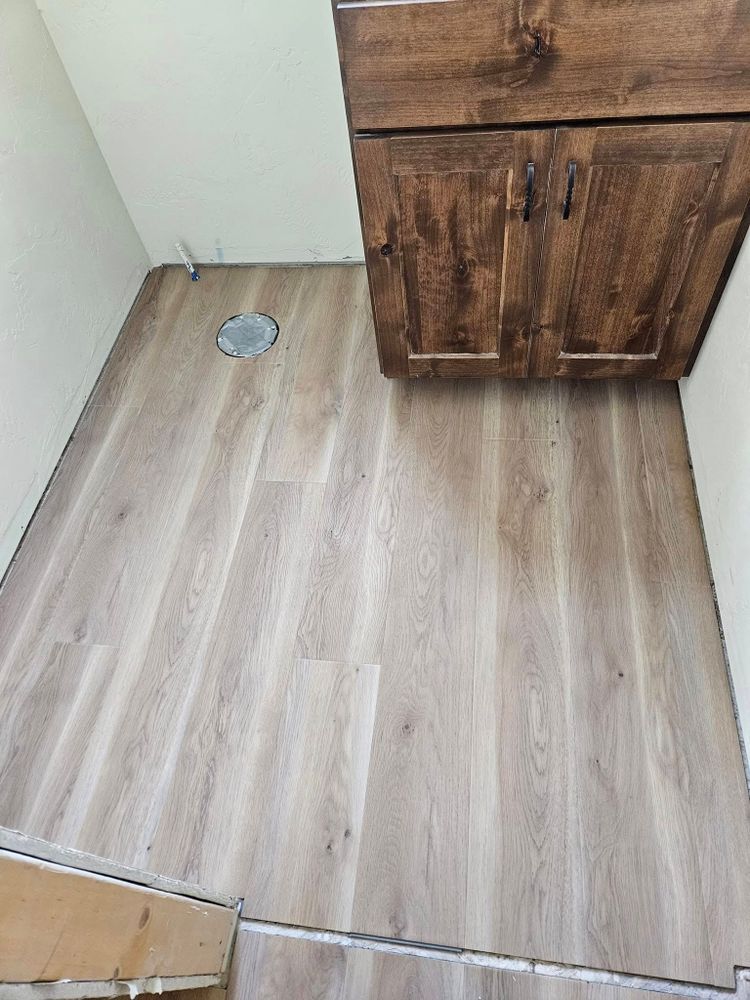 Light wood-look flooring in a small space with a dark brown cabinet above.