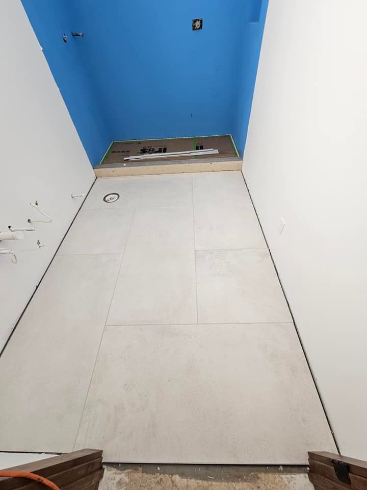Bathroom under construction; light gray wall tiles, blue ceiling.