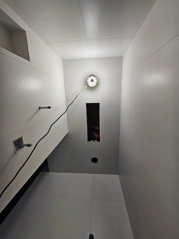 Narrow, white-walled room with a central ceiling light, a small window, and gray flooring.