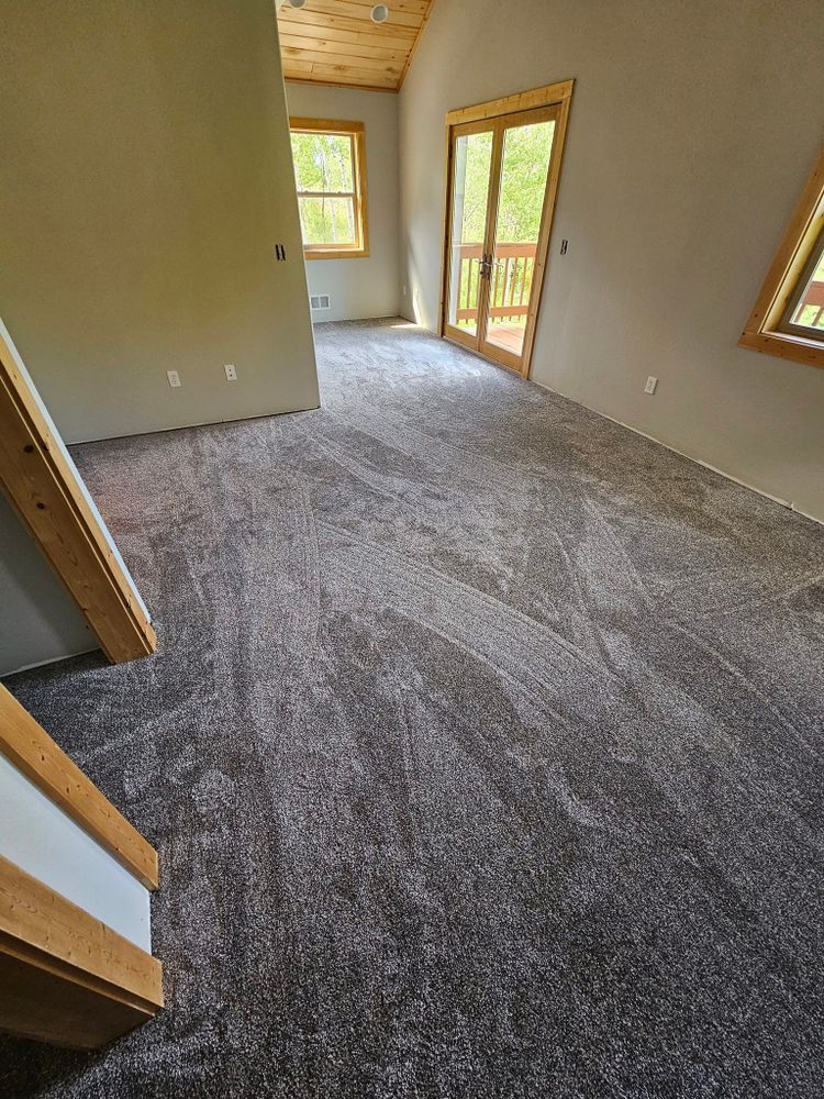Empty room with gray carpet, beige walls, wooden trim, and a sliding glass door to a deck.