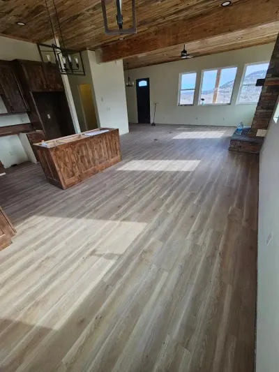 Interior of a home with light wood floors, a dark wood island, and exposed wood beams on the ceiling.