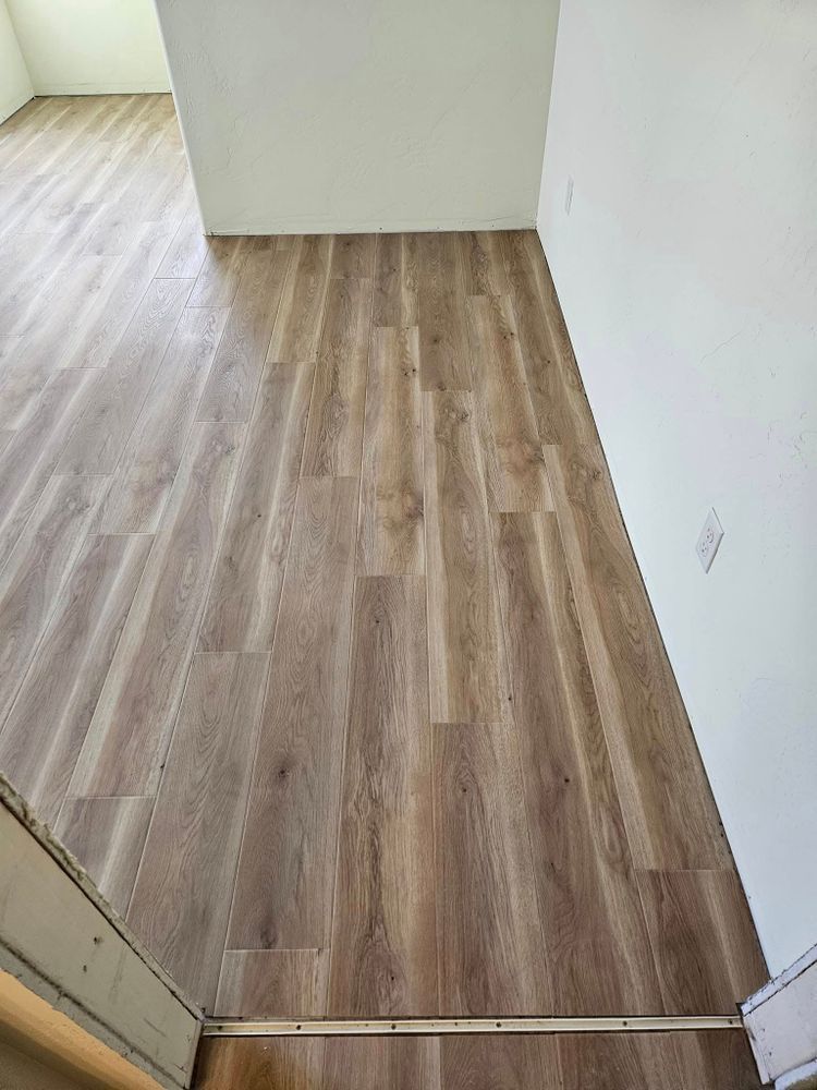 Wooden-look flooring leading into a hallway with white walls and a stair edge visible.
