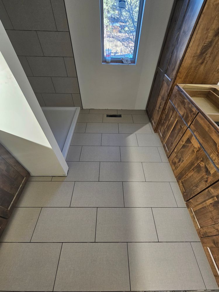 Narrow room with light-colored tile floor, wooden cabinets, a small window, and white walls.