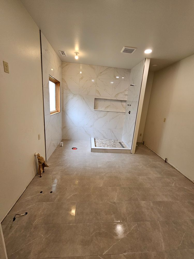 Empty bathroom with marble tile, shower, and unfinished walls.
