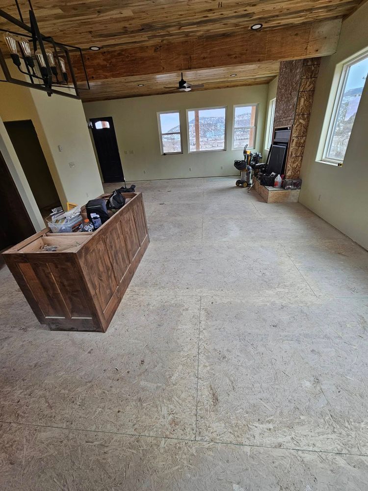 Empty living room with wooden ceiling, fireplace, and exposed subfloor.