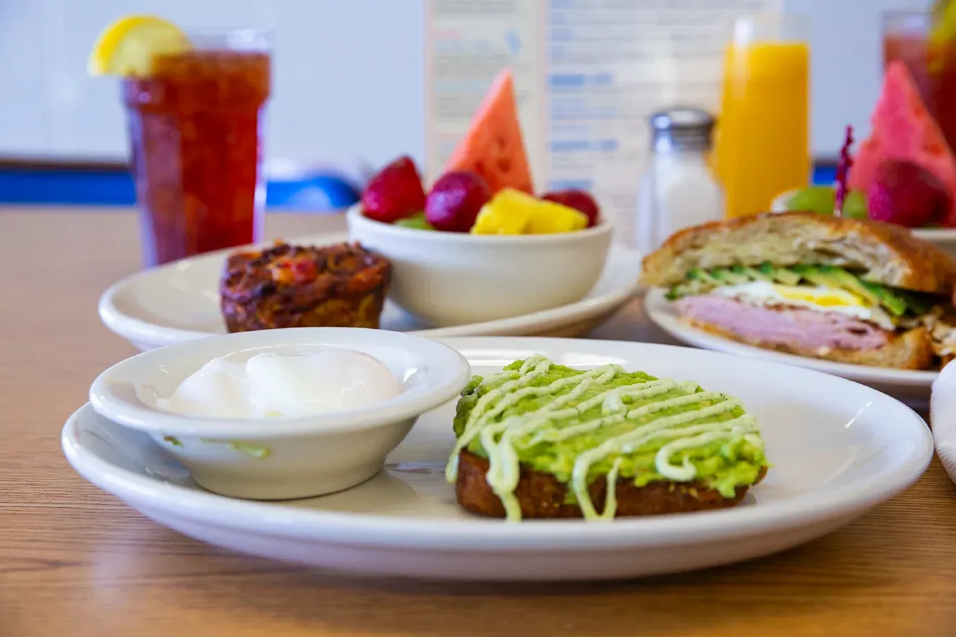 A plate of food with avocado toast and fruit on a table.