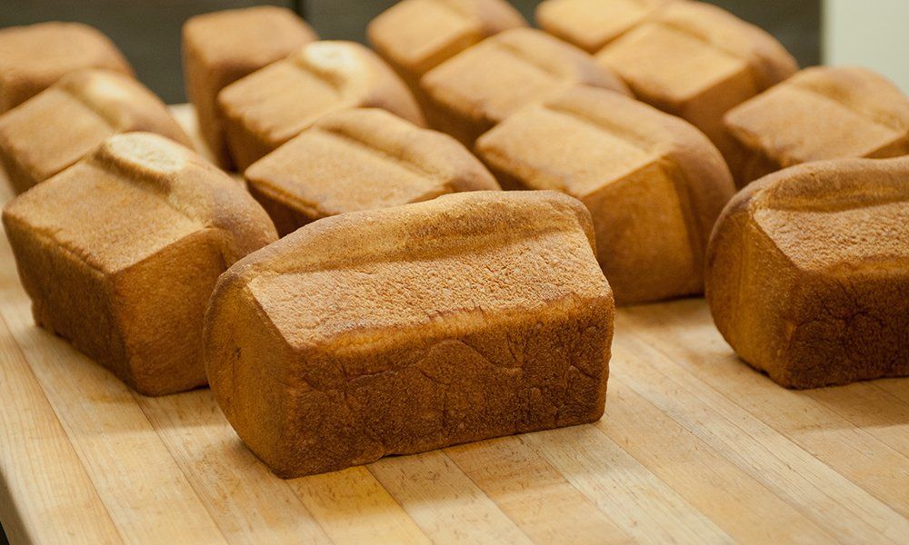Several loaves of bread are sitting on a wooden cutting board.