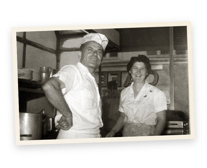 A black and white photo of a man and woman in a kitchen