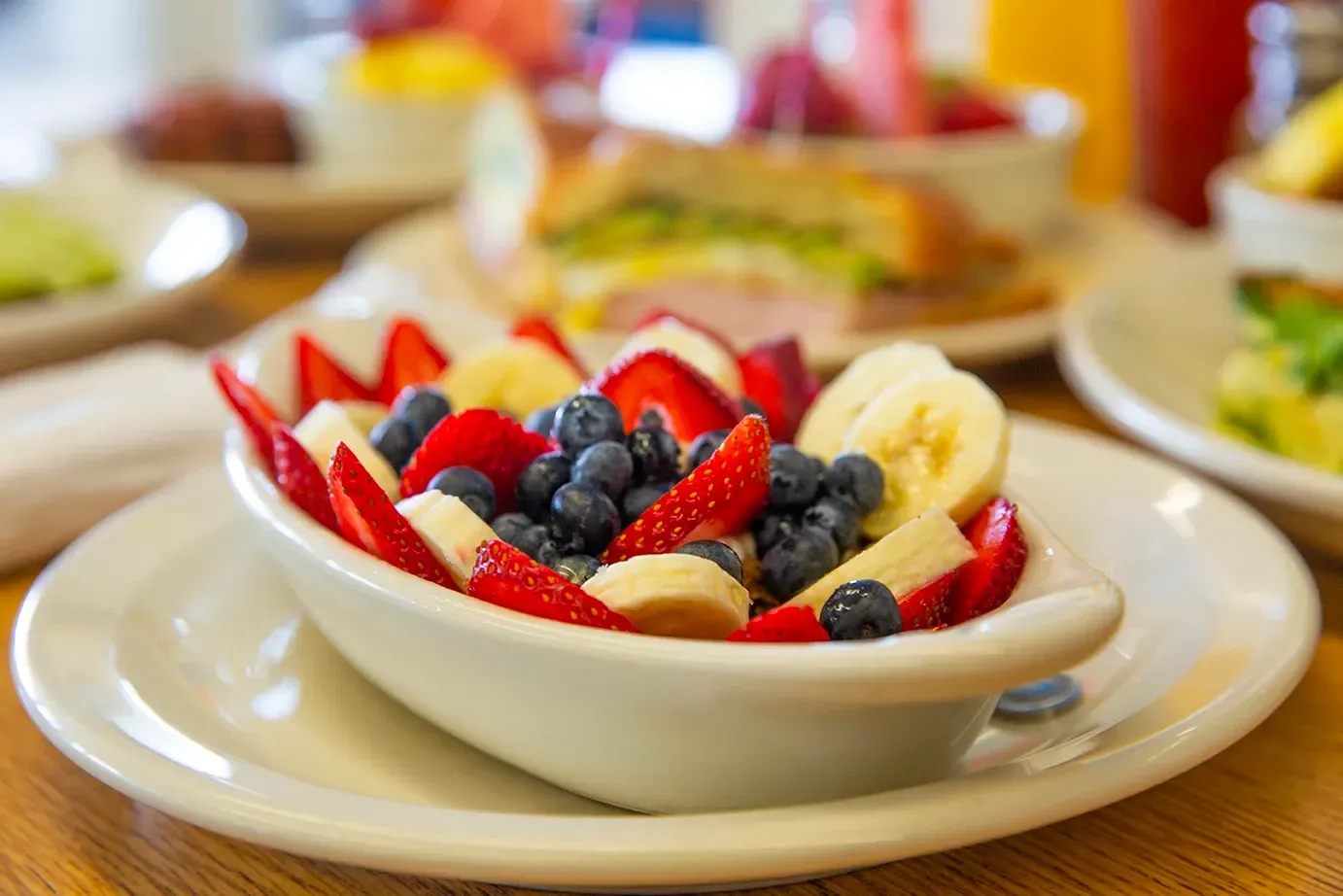 A bowl of yogurt parfait on a plate on a table.